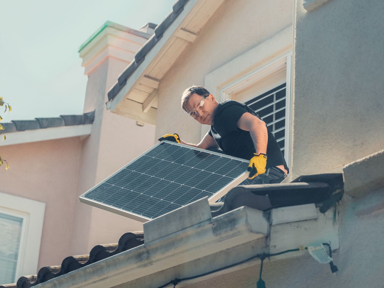 Mastering the First Impression: Your intriguing post title goes here A technician in protective gear installs solar panels on a house roof, promoting sustainability.